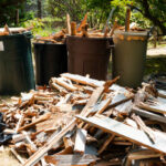 Piles of wood on the ground and in garbage pails left from removing a wood deck in a backyard.