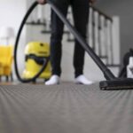 Man vacuuming the carpet in the room. House cleaning process